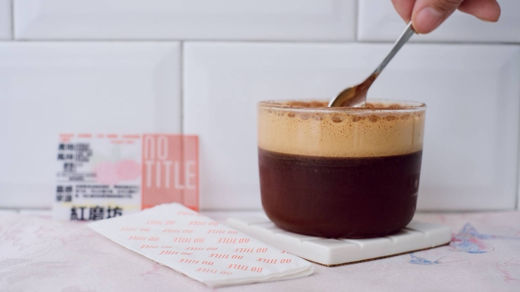A layered coffee beside a No Title Coffee Design card